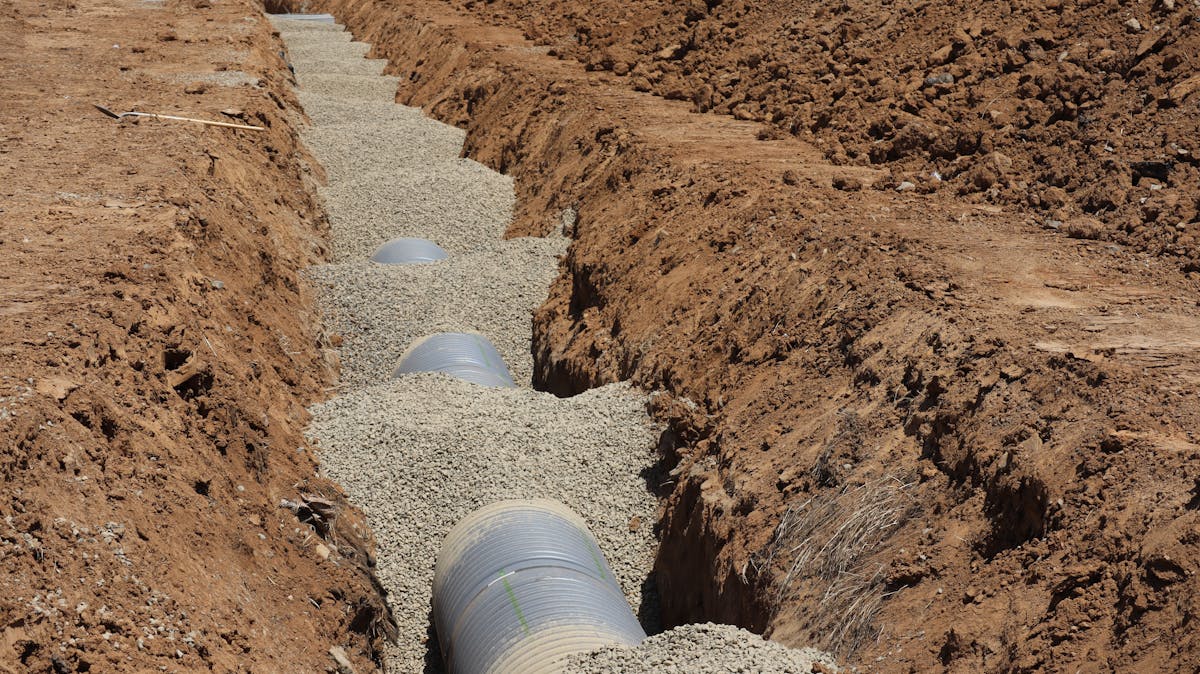 Slotted drainage pipe bedded in gravel in an open trench
