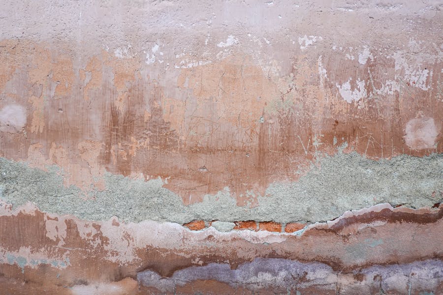 Wall with chipped and crumbling plaster falling away from the surface