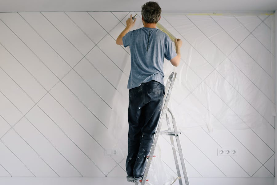House painter rolling a sealer coat onto a bare wall in a bright room
